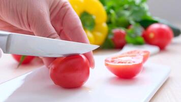 mulher corte cebolas e legumes em corte borda fechar-se do fêmea mãos fatiamento cereja tomate com faca em de madeira quadro, cozinhando vegetal salada video