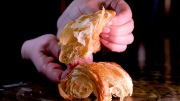 fresh croissant the porous structure of baking inside the woman is stretching it in different directions crumbs are pouring in breaking a freshly baked dessert french eating breakfast with hands video