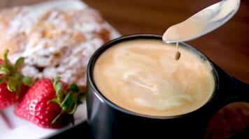 Delicious coffee view with wheat. black mug coffee with foam spoonful strawberry croissant video