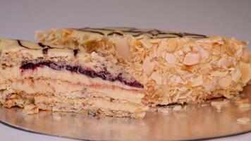 Piece of a puff pastry cake, sprinkled crumbs, with custard cream is placed with a cake spatula on a glass plate video