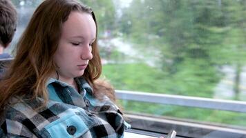 tren ventana móvil teléfono manos de joven niña montando en carro viaje red Wifi calentar tartán chaqueta blanco teléfono caso escucha a música Mira para Noticias corresponder con amigos Desplazarse mediante alimentar video