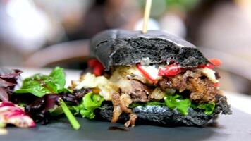 bitten burger with jamon, tomato, lettuce and onion on wooden table video