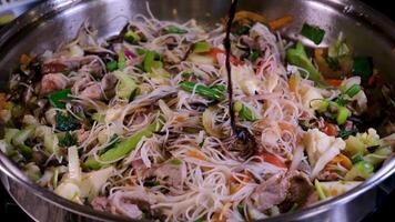 versare soia salsa in un' frittura padella cucinando asiatico cucina vermicelli wok con verdure e Manzo carne agitare frittura frutti di mare bicchiere tagliatelle video