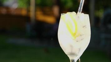 gießen Limonade mit Eis Eis in ein Glas gießen Limonade Wasser werfen Zitrone rühren mit ein Stroh mehrere Videos von ein kalt trinken auf das Straße auf das Tabelle sprudelnd Schaum Luftblasen Nahansicht