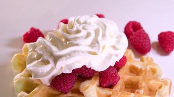 Person eating soft Belgian waffles using a fork, cutting a piece of sweet fluffy waffle with cream topping and chocolate syrup, served with fresh berries, close up , high quality 4k footage video