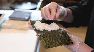 capocuoco cucinando il riso per delizioso Sushi a il asiatico ristorante. cucinare mette un' fetta di salato crudo salmone su superiore di il palla di Sushi Riso. cucinando il Sushi utilizzando pesce e riso ingredienti. sashimi. video