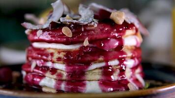 stack of delicious pancake decorated with coconut flakes blueberries hazelnuts almond flakes raspberries and jam delicious breakfast with sour cream eaten with fork in restaurant beautiful serving video