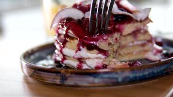 stack of delicious pancake decorated with coconut flakes blueberries hazelnuts almond flakes raspberries and jam delicious breakfast with sour cream eaten with fork in restaurant beautiful serving video