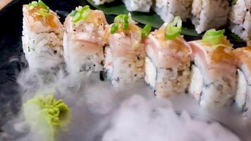 heerlijk restaurant Aziatisch voedsel sushi Aan bord met droog ijs paling tonijn reeks omhullend allemaal in de omgeving van ruimte voor tekst reclame sushi portie menu chef cursussen sushi maker detailopname ongelooflijk heerlijk video