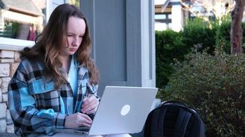 Image of a young beautiful joyful woman smiling while working with a laptop outdoors on the porch beautiful young teen girl video