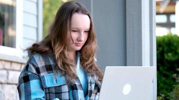 un contento joven mujer es utilizando su ordenador portátil sentado en el banco fuera de en el calle video