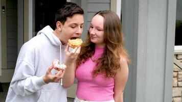 gusto cibo mordere ciambella dare un' gusto di il tuo dolcezza ragazza offerte per provare ciambella per ragazzo amici fratello sorella su veranda mangiare dolci adolescenti avendo divertimento adolescenza vicino relazioni gentilezza Condividere video