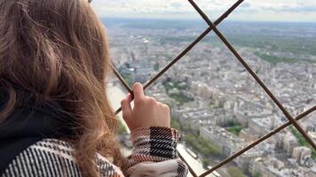 A girl on a eiffel tower looks around at the city of Paris visible houses the Seine River with boats and the city center 06.04.22 Paris France video