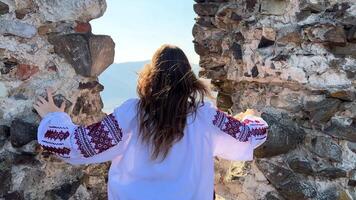 No war Ukrainian young girl in an embroidered blouse on the ruins of an old castle sad sadly and looks at everything around video