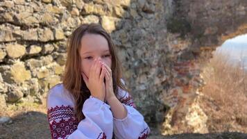 No guerra ucranio joven niña en un bordado blusa en el restos de un antiguo castillo triste tristemente y mira a todo alrededor video