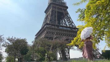 a girl in a long dress with an openwork umbrella goes to the eiffel tower with her back to the camera can be used for advertising text for the interior very beautiful slow motion video