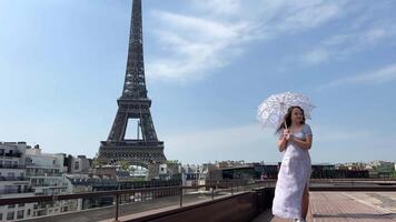 fille en marchant avec ajouré parapluie le parfait toile de fond pour tout récit à propos Paris une mince fille regards en haut à le Eiffel la tour mais tout nous voir est une parasol et une bleu ciel le photo video