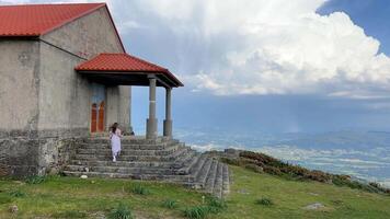 une Jeune fille court en haut le pas de le église lequel est situé sur une haute Montagne autour le espace là est une lot de espace pour texte sans fond beauté video