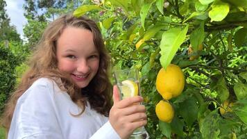 niña en un blanco camisa adolescente teniendo divertido biatlón en el antecedentes de un limón árbol agua con limón video