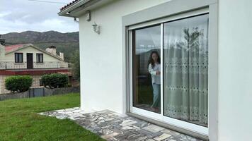 un niña todas en blanco carreras a lo largo el verde césped en contra el fondo de un blanco casa y luego un negro gato cruces su camino niña detener lo hace no saber qué a hacer a aleatorio o no video