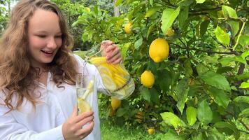 Vad skulle kunna vara bättre än Häftigt citronsaft i en varm sommar en flicka står med en kanna i henne hand och är mycket Lycklig hon häller citronsaft i de bakgrund hon har en citron- träd video