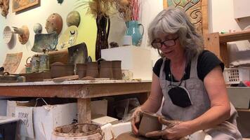 adult Seda hairy woman made a product on a potter's wheel she takes it puts it on the table and tries on a lid on it Does she fit the size of her hand in clay She smiles happily turns into frame video