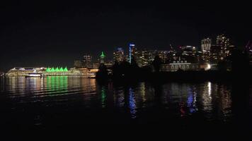 Mirror reflection of the whole city in the ocean Dark night in Canada Vancouver view from ocean luminous building Canada Place sails in green Skyscrapers glow with many lights reflected in the water video