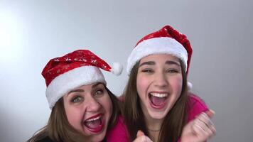 Screaming and jumping friendship joy fun Christmas positive emotions mom and daughter rejoice in the holiday They wear red Christmas hats New Year's party at home with a thumbs up and dance video