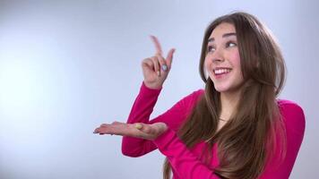 menina anuncia com dela mãos fofa menina com grandes Castanho cabelo pontos para a esvaziar espaço para texto e então ondas dela dedo avisando isto produtos e então voltas para a Câmera e mostra uma polegares acima classe video