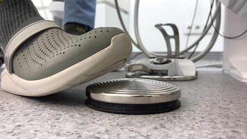 a gray slipper on the foot of a man who presses a button under the seat in a dental clinic in order to remove caries or fill a tooth, as well as for various dental work video