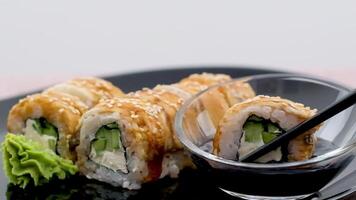 tremper un Sushi Rouleaux dans soja sauce sur noir Contexte. fermer trempettes le Rouleaux dans le soja sauce sur une noir Contexte. baguettes à tremper le Rouleaux dans soja sauce, fermer. video