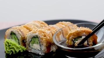 tremper un Sushi Rouleaux dans soja sauce sur noir Contexte. fermer video