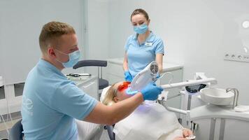 dental clínica dientes blanqueo mujer acostado debajo aparato médico y enfermero mujer manos participación pánico botón más allá polusa más avanzado blanqueo sistema con dental uv láser blanqueo dispositivo video