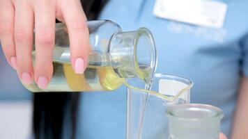 Closeup professional scientist pours clear yellow liquid extracted from oil into lab glass in refinery factory laboratory video