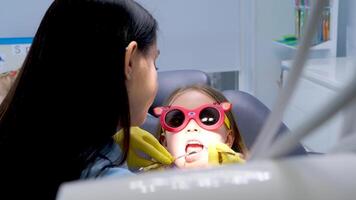 pediatric dentistry close-up little girl opened mouth shows teeth doctor looks at whether she has caries fillings treatment examination by doctor shine in eyes yellow hygienic gloves video