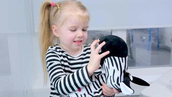 ein Mädchen im ein gestreift Bluse untersucht ihr Zähne beim ein Zebra Spielzeug ein Besondere Modell- zum Bürsten ein Zahn Lehren Kinder richtig Oral Pflege Dental Büro Interesse schön süß Kind video