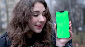 Use green screen for copy space closeup. Chroma key mock-up on smartphone in hand. Woman holds mobile phone iPhone and swipes photos or pictures left indoors of cozy home video