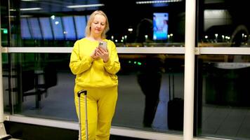 Airport Terminal. Happy Traveling Woman Walks to Her Flight Gates, Uses Smartphone, Browsing the Internet with App, Checking Traveling Destination. Female Walking Through Hallway of Airline Hub video