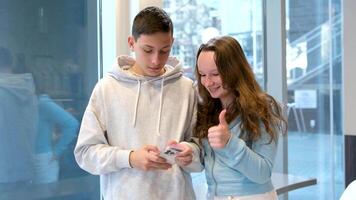 Leben von Jugendliche auf das Telefon ein Junge und Mädchen sitzen beim Tabelle durch Fenster jeder mit ihr Smartphone verbringen Zeit auf Internet im Sozial Netzwerke Cafe Schule Cafeteria nehmen Bilder von jeder andere schießen Videos