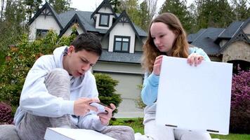 estudiante años colegio hora adolescentes chico niña con Pizza cajas artilugio en claro en césped asentar cobija contento contento jugar comunicar real vida en Canadá America Europa en privado sector Rico vida video