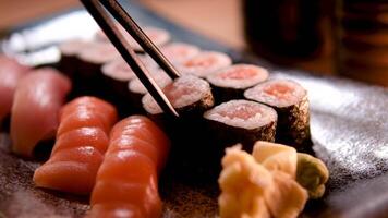 Sushi einstellen lecker und appetitlich Sushi. Sushi mit Scheiben von Lachs und frisch Gurken. rot Ingwer und Grün Wasabi auf ein hölzern Tafel wurden serviert zu Sushi. Sushi rot Drachen video