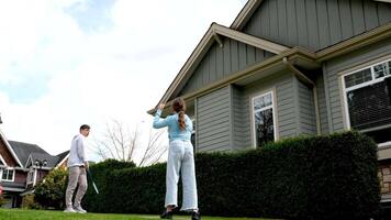 adolescence friends playing badminton boy and girl teenagers private sector of houses sky with clouds sportswear jeans brother and sister to visit Canadian village children Surrey Vancouver together video