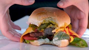 nehmen ein beißen Zuhause gemacht Rindfleisch Burger mit Grüner Salat und Mayonnaise serviert auf wenig hölzern Schneiden Tafel. video