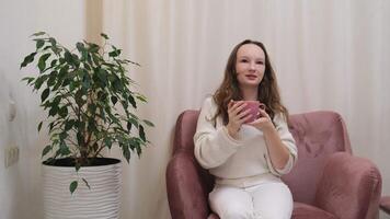 Frau im Weiß jung Mädchen im ein Rosa Stuhl genießt Trinken ein trinken und mit ein Rosa Tasse Trinken Kräuter- Tee Kaffee entspannend mit freunde Lachen Lächeln reden haben ein Konversation video