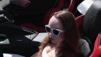 Luxurious car and girl A girl sits behind the wheel of a red car with her hands up, enjoys life, a rich life, a lot of money. video