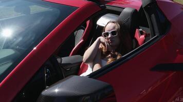 Luxurious car and girl A girl sits behind the wheel of a red car with her hands up, enjoys life, a rich life, a lot of money. video