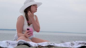 Girl using cellphone on a sea ocean shore. Young girl on the beach with your smartphone. video