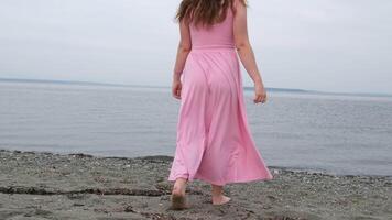 White hat Girl in a pink dress on the ocean A wide shot of a teen strolling barefoot at the beach video