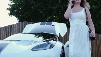 blanco elegante lujo coche un niña en un blanco vestir camina dentro el distancia hablando en el teléfono video