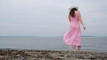 White hat Girl in a pink dress on the ocean A wide shot of a teen strolling barefoot at the beach video